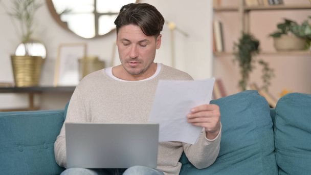 Middle Aged Man with Documents working on Laptop , at Home - Photo, Image