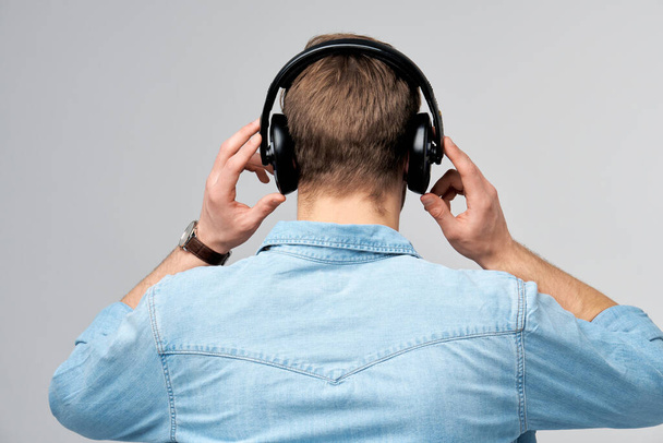 Close up portrait of cheerful young man enjoying listening to music wearing casual jeans outfit - Foto, Bild
