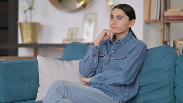 Worried Latin Woman with Laptop Thinking on Sofa - 写真・画像