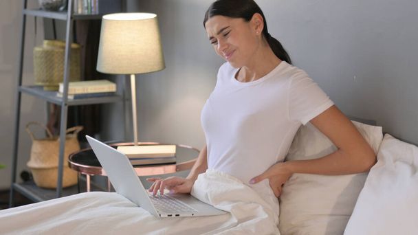 Laptoplu Latin Kadın Yatakta Sırt Ağrısı Var  - Fotoğraf, Görsel