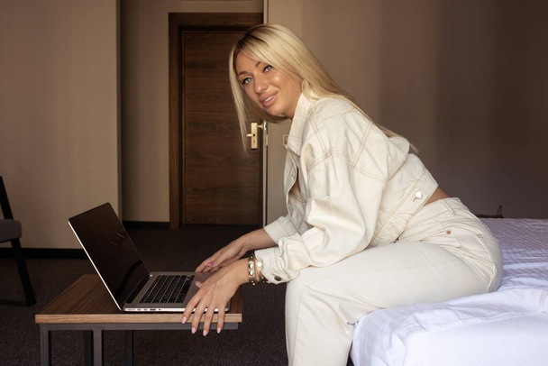Young woman using laptop in a hotel bedroom. - Fotó, kép