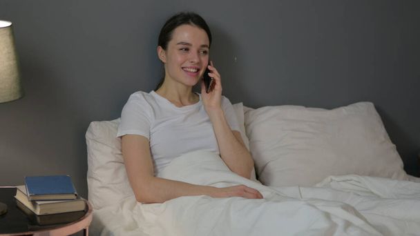 Giovane donna che parla su smartphone a letto  - Foto, immagini