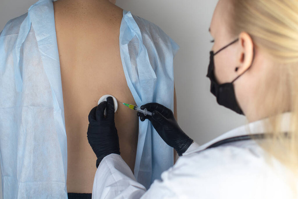 Le médecin spécialiste des maladies infectieuses fait une vaccination médicale au patient dans l'omoplate. Immunisation contre le tétanos, la grippe, la diphtérie, l'encéphalite transmise par les tiques et l'hépatite B - Photo, image