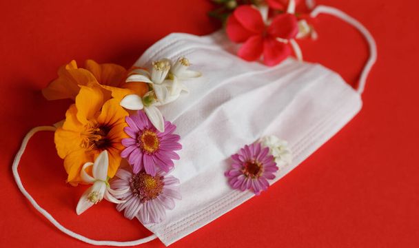 medizinische Maske Blumen auf der Oberseite mit unterschiedlichen Farben Blumen auf rotem Hintergrund. Seitenansicht - Foto, Bild