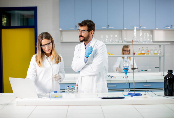 Ερευνητές που εργάζονται με μπλε υγρό σε διαχωριστική χοάνη στο εργαστήριο - Φωτογραφία, εικόνα