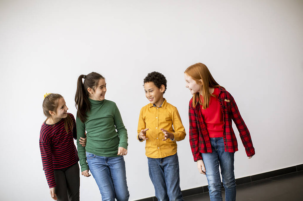 Portrait of cute little kids in jeans  talking and smiling, walking against the white wall - Fotó, kép