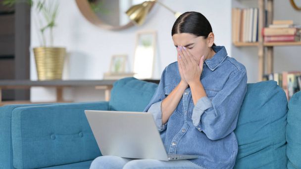 Latin Woman with Laptop Sneezing on Sofa  - 写真・画像