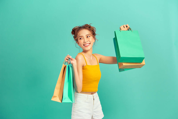 Feliz joven asiática sosteniendo bolsa de compras en verano sobre fondo verde claro. - Foto, Imagen