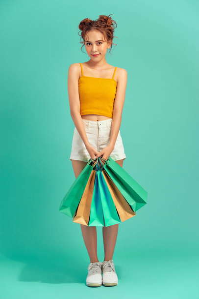 Glückliche junge Asiatin mit Einkaufstasche im Sommer vor hellgrünem Hintergrund. - Foto, Bild
