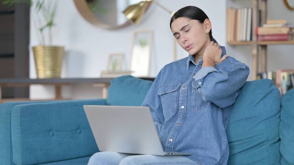 Работа на ноутбуке Латинская женщина с болью в шее на диване  - Фото, изображение