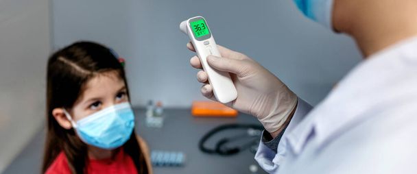 Kobieta lekarz patrząc na termometr podczerwieni po zrobieniu tempe - Zdjęcie, obraz