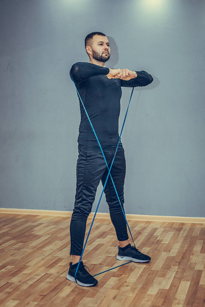Vertical, full-length sportsman workout with loop band, stretch resistance rope with feet and arms, look sideways determined and serious, fitness training. - Foto, Imagen