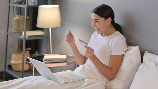Латинська жінка онлайн успіх покупок на ноутбуці в ліжку
  - Фото, зображення