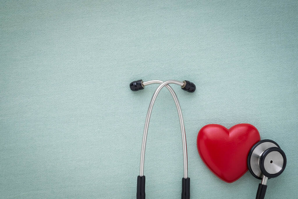 Black stethoscope with red heart of doctor for check up on light green background. Stethoscope equipment of medical use to diagnose hear sound. Health care and cardiology concept with copy. - 写真・画像