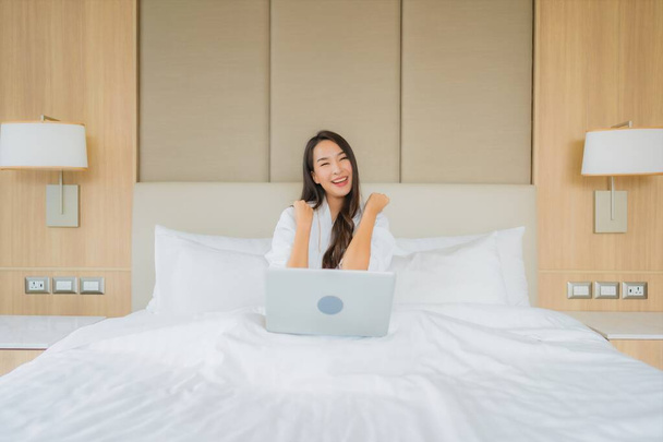 Портрет красива молода азіатка використовує ноутбук в інтер'єрі спальні
 - Фото, зображення