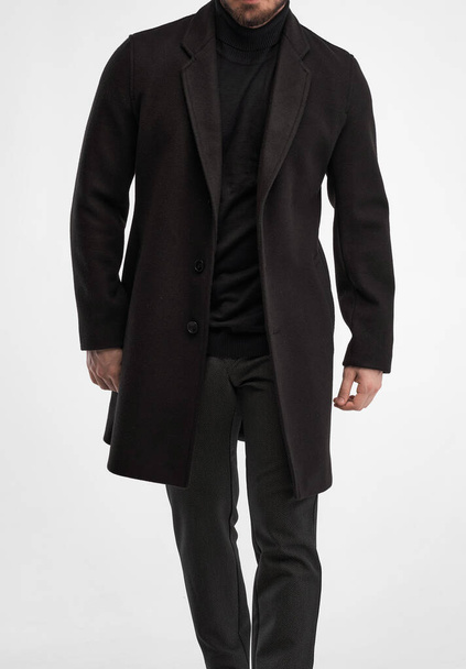 De man draagt een zwarte jas. geïsoleerde studio shot van stijlvolle man in donker full length greatcoat - Foto, afbeelding