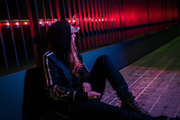 Beautiful cinematic portrait of stylish young woman in neon lighted fence. Bright neoned colors. Caucasian model, musician outdoors. Youth culture and music concept. - Fotoğraf, Görsel