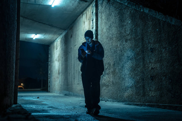 Lonely man with his smart phone in a dark alley at night. Danger and scary concept. - Fotografie, Obrázek