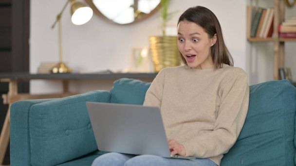 Mujer joven emocionada con el ordenador portátil maravillándose con asombro  - Foto, Imagen