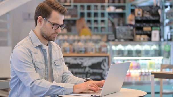 Jeune homme créatif travaillant sur ordinateur portable à Cafe  - Photo, image