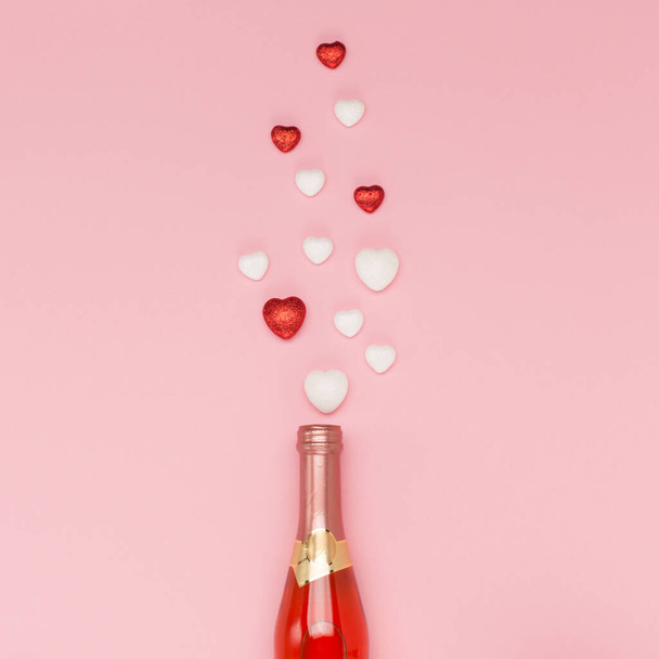 Pullo viiniä ja punaisia valkoisia sydämiä vaaleanpunaisella taustalla. Ystävänpäivän konsepti. Tasainen lay, ylhäältä näkymä, kopioi tilaa. Juhlapyhien onnittelukortti Ystävänpäivä, Syntymäpäivä, Nainen tai Äitienpäivä. - Valokuva, kuva