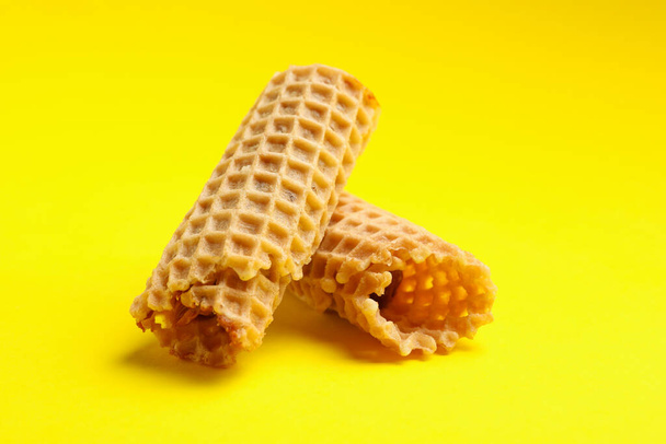Tasty wafer rolls with condensed milk on yellow background - Fotó, kép