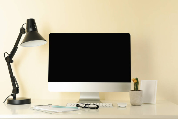 Werkplaats met desktop computer tegen beige achtergrond - Foto, afbeelding