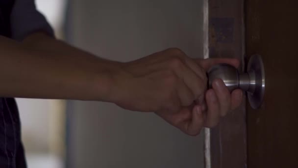 A férfi kinyitja az ajtó kulcsát és belép a szobába és becsukja az ajtót, fényes háttér a fa ajtó mögött - Felvétel, videó