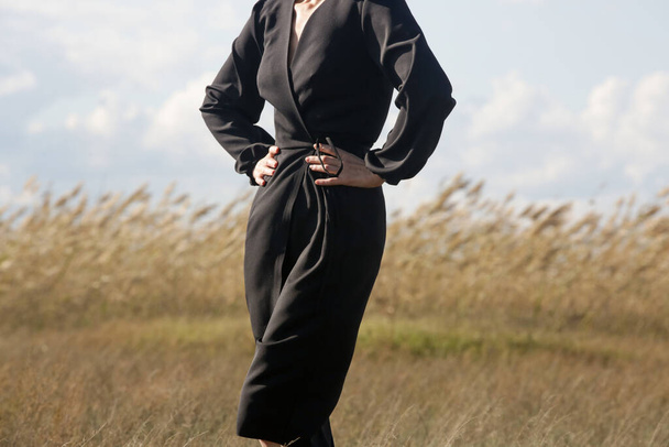 Outdoor fashion portrait of Caucasian woman in black wrapped long sleeve dress - Zdjęcie, obraz