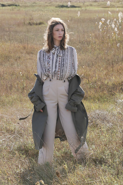 Outdoor mode portret van blanke vrouw in brede been beige broek en groene trench jas. - Foto, afbeelding