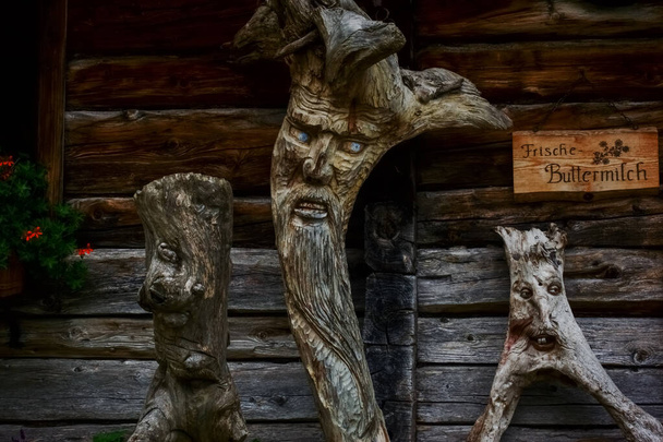 faces carved in tree trunks standing on a house in the mountains while hiking - Photo, Image