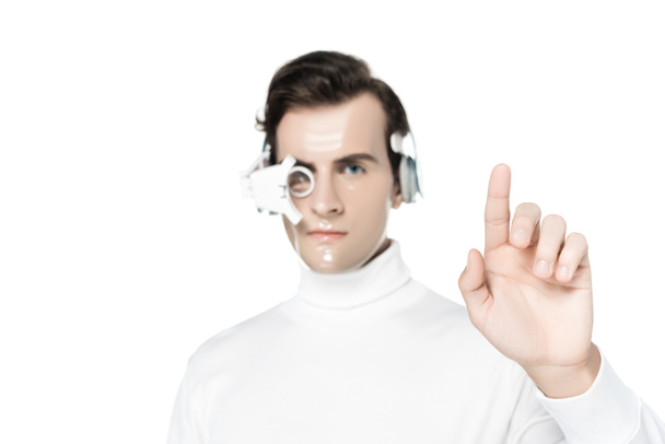 Cyborg in digital eye lens and headphones on blurred background pointing with finger isolated on white - Photo, Image