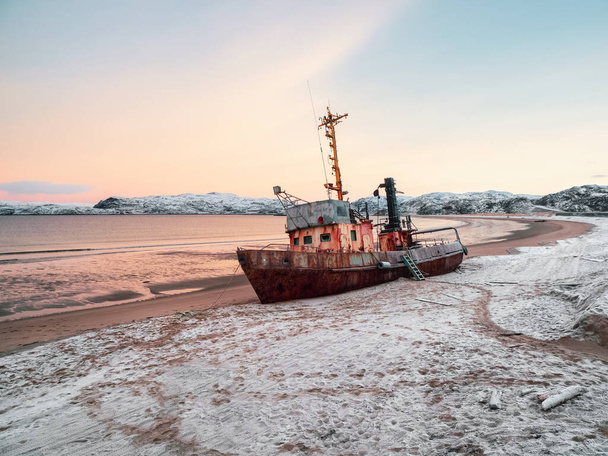 Barents Denizi 'nde kumlu bir sahilde eski paslı bir balıkçı teknesi kıyıya vurmuş. Otantik Kuzey Denizi. - Fotoğraf, Görsel