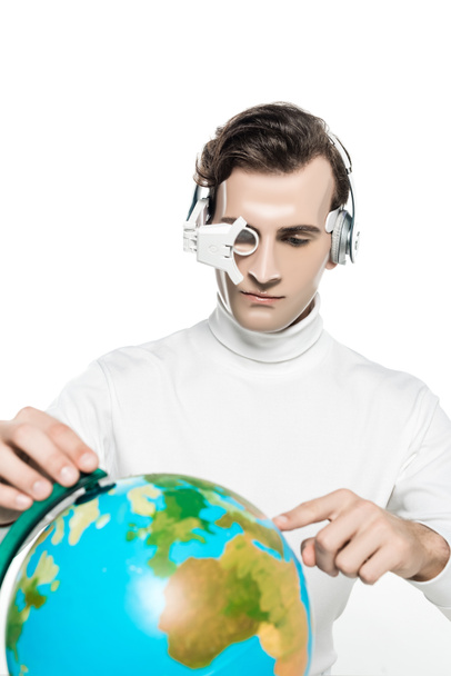 Cyborg hombre en lente de ojo y auriculares apuntando a globo en primer plano borroso aislado en blanco - Foto, Imagen