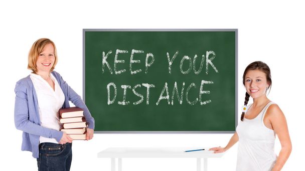 Jeune professeur et écolière devant un tableau, gardez vos distances est écrit sur le tableau, isolé sur fond blanc - Photo, image