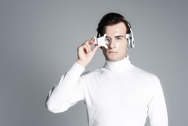 Cyborg in headphones holding digital eye lens isolated on grey - Fotografie, Obrázek