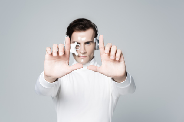 Кіборг людина в навушниках на розмитому фоні торкається чогось ізольованого на сірому
 - Фото, зображення