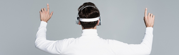 Zadní pohled na kyborg ve sluchátkách dotýkající se něčeho izolovaného na šedé, banner - Fotografie, Obrázek