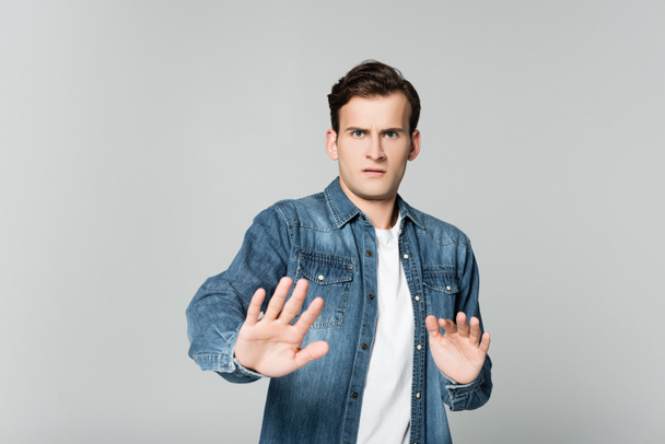 Scared man showing stop gesture isolated on grey - Photo, image