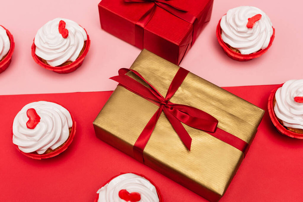 cupcake di San Valentino vicino a scatole regalo su sfondo rosa e rosso - Foto, immagini