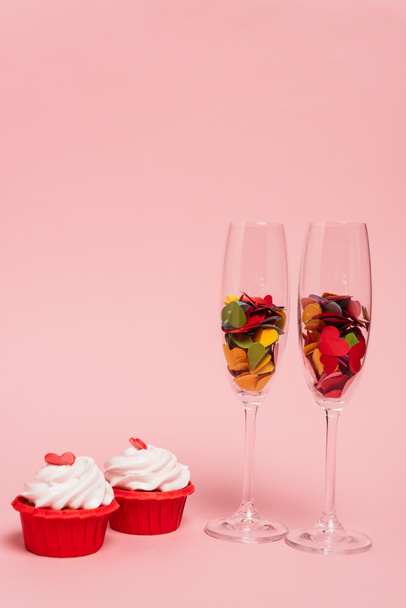 colorful hearts in champagne glasses and cupcakes on pink - 写真・画像
