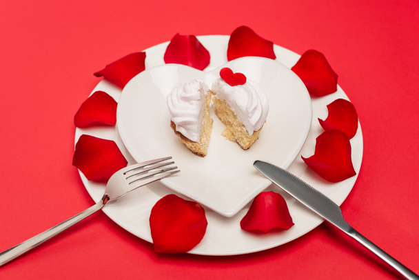 cupcake on plate with rose petals and cutlery on red background - Фото, изображение