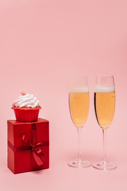 champagne glasses near gift and cupcake isolated on pink - Foto, Imagem