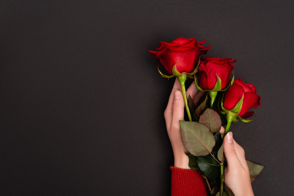 Kırpılmış görüntüde, elinde kırmızı güller tutan siyah bir kadın. - Fotoğraf, Görsel