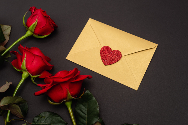top view of roses and valentines envelope isolated on black - Foto, imagen