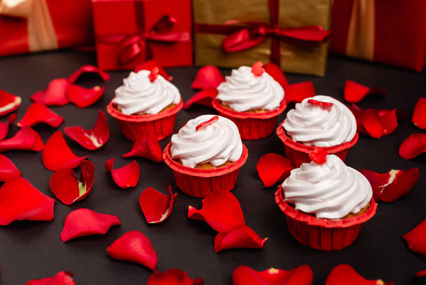Rosenblätter und Valentin Cupcakes isoliert auf schwarz - Foto, Bild