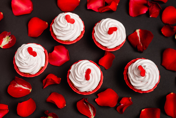 top view of rose petals and valentines cupcakes isolated on black - Photo, Image