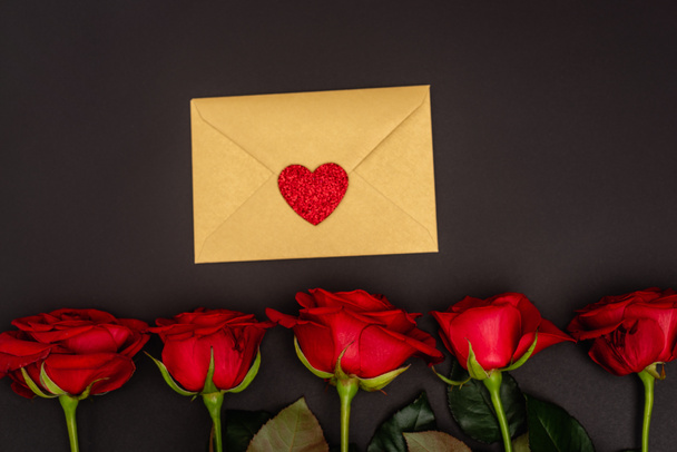 top view of roses and envelope isolated on black - Foto, Imagen