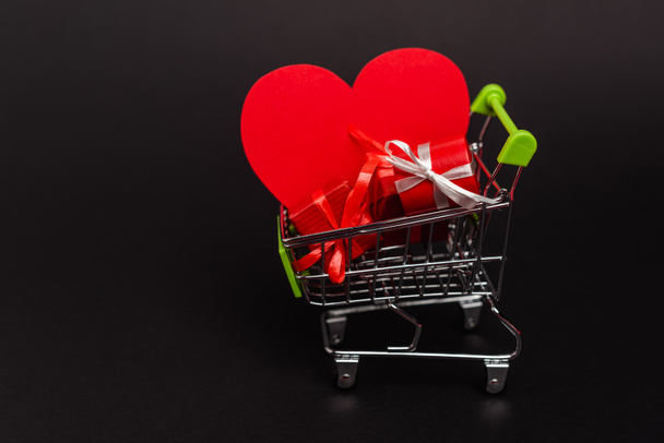 shopping cart with valentines gifts and heart isolated on black - Fotó, kép
