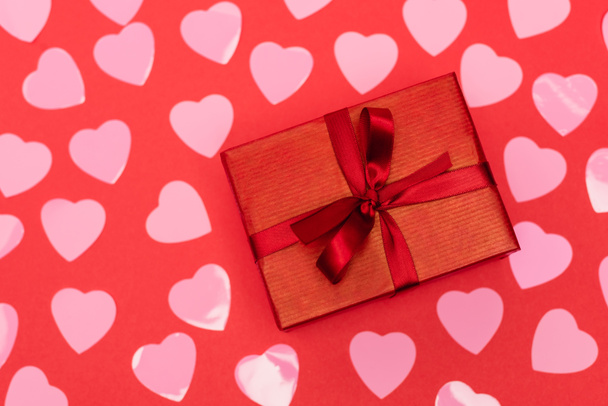 vue du haut des cœurs roses et boîte cadeau sur fond rouge - Photo, image